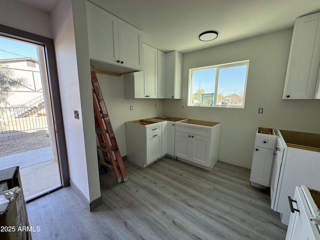 kitchen featuring a healthy amount of sunlight, white cabinetry, range, and light hardwood / wood-style floors