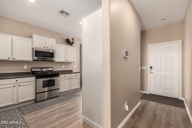 152 N 194th Ln, Buckeye, AZ 85326 - kitchen featuring light wood-type flooring, white cabinetry, dark countertops, visible vents, and stainless steel appliances