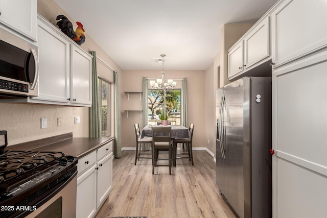 152 N 194th Ln, Buckeye, AZ 85326 - kitchen featuring an inviting chandelier, white cabinetry, appliances with stainless steel finishes, decorative light fixtures, and light wood finished floors
