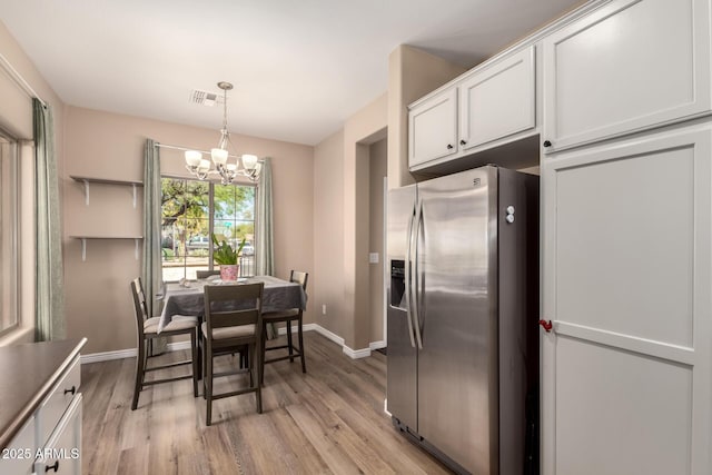 152 N 194th Ln, Buckeye, AZ 85326 - kitchen with white cabinetry, an inviting chandelier, baseboards, and stainless steel fridge