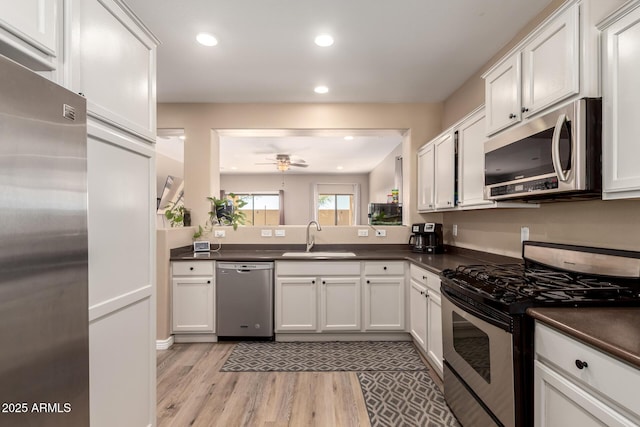 152 N 194th Ln, Buckeye, AZ 85326 - kitchen featuring light wood-style flooring, a ceiling fan, dark countertops, appliances with stainless steel finishes, and a sink