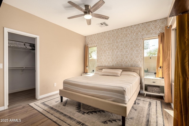 152 N 194th Ln, Buckeye, AZ 85326 - bedroom featuring baseboards, wallpapered walls, an accent wall, visible vents, and wood finished floors
