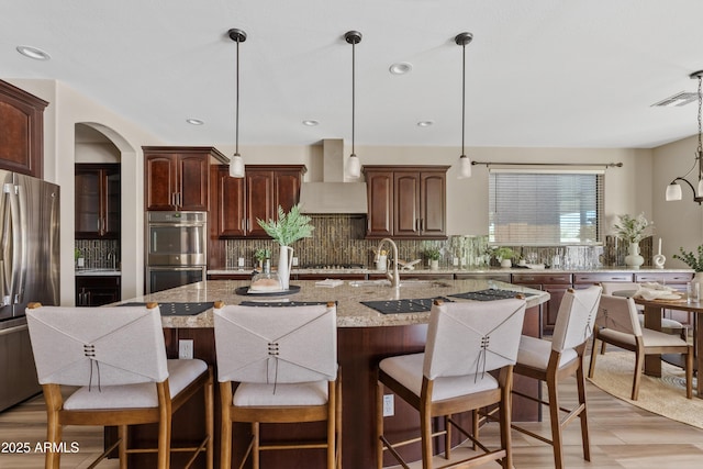10331 E Starion Ave, Mesa, AZ 85212 - kitchen featuring wall chimney range hood, appliances with stainless steel finishes, tasteful backsplash, a kitchen bar, and recessed lighting