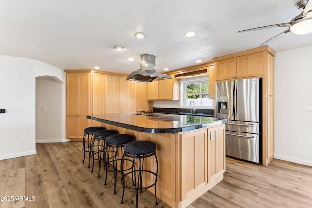 kitchen with stainless steel refrigerator with ice dispenser, island range hood, light brown cabinetry, and light hardwood / wood-style flooring