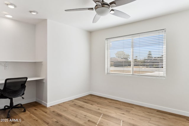 office space featuring built in desk, ceiling fan, and light hardwood / wood-style flooring