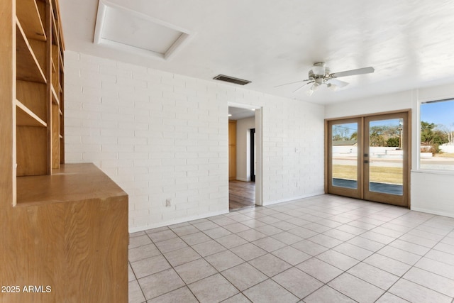 empty room with french doors, ceiling fan, brick wall, and light tile patterned floors