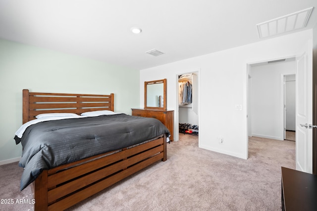 bedroom featuring light carpet, a walk in closet, and a closet