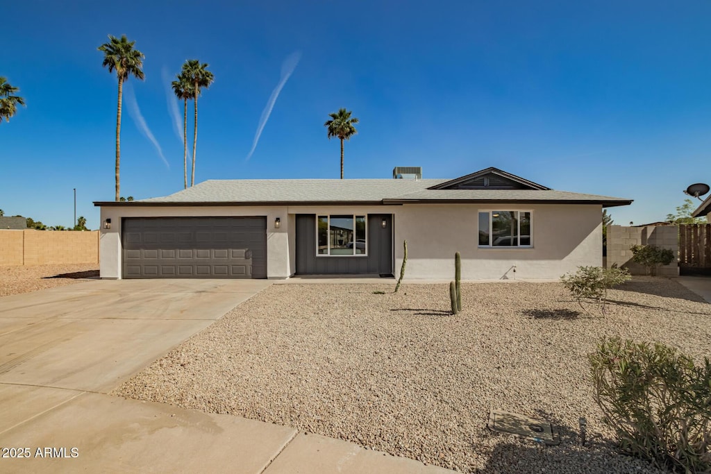 ranch-style house featuring a garage, stucco siding, fence, and concrete driveway