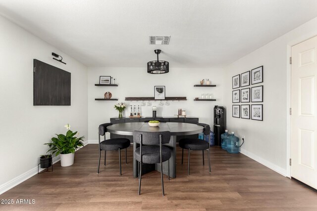 dining space with baseboards, visible vents, and wood finished floors