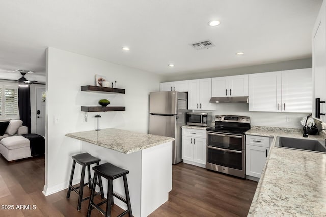 kitchen featuring visible vents, stainless steel appliances, under cabinet range hood, a sink, and open shelves