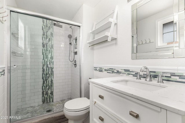 bathroom with toilet, vanity, and a stall shower