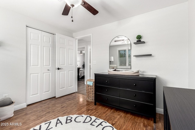 bedroom featuring baseboards, a closet, wood finished floors, and ceiling fan