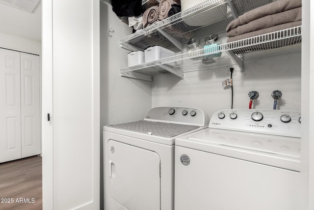 clothes washing area featuring separate washer and dryer, visible vents, and light wood-type flooring