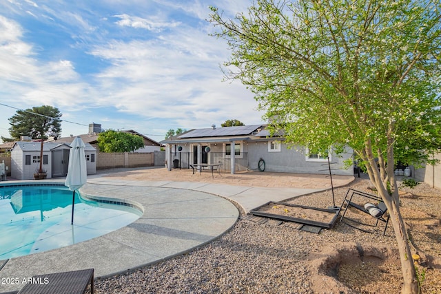 view of swimming pool featuring a patio, an outbuilding, a fenced backyard, and a shed