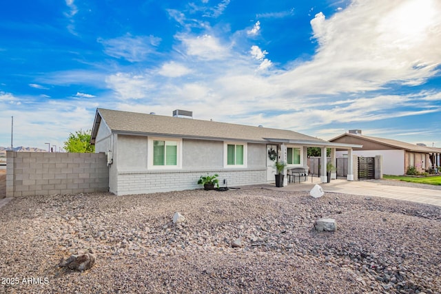 ranch-style home with stucco siding, brick siding, and fence