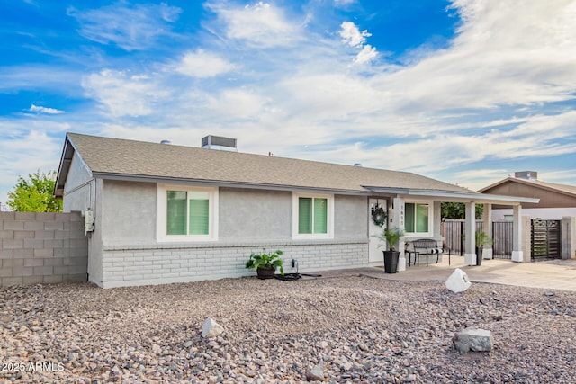 ranch-style home featuring brick siding, stucco siding, fence, and a patio area