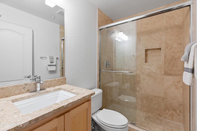 bathroom with vanity, a shower with door, and toilet