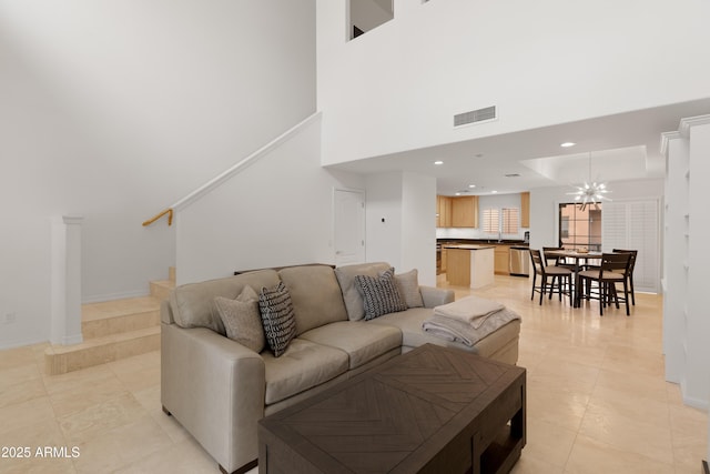 living room featuring a notable chandelier, light tile patterned floors, and a high ceiling