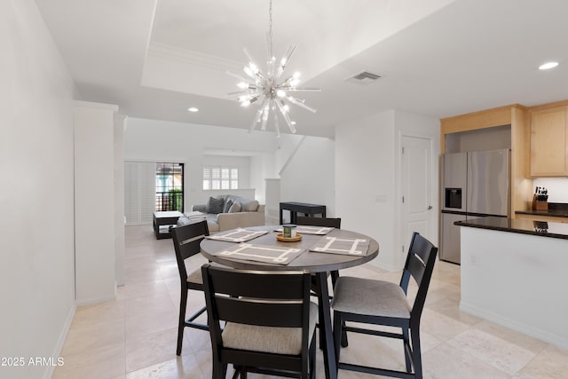 tiled dining area with a raised ceiling and a chandelier