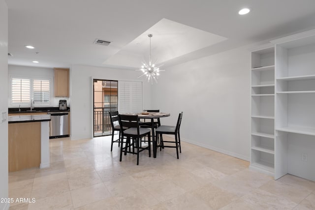 dining space with built in shelves, sink, an inviting chandelier, and a tray ceiling