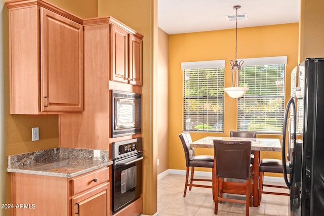 kitchen featuring black fridge, stainless steel microwave, wall oven, decorative light fixtures, and light tile floors