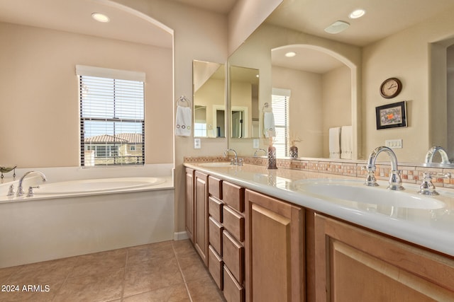 bathroom with tile flooring, a washtub, vanity with extensive cabinet space, and double sink