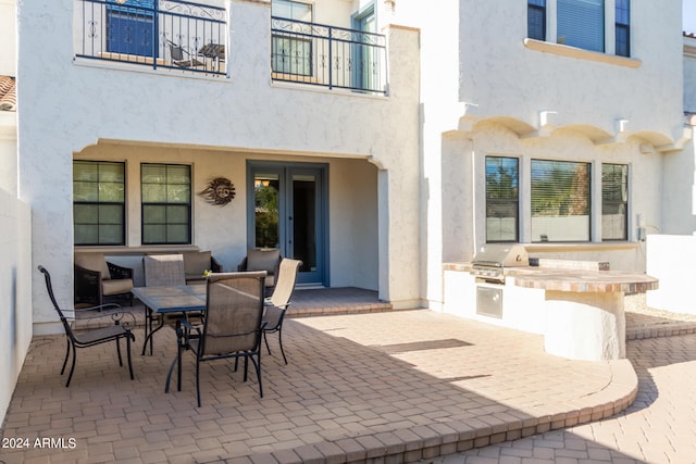 view of patio with a grill, exterior kitchen, and a balcony