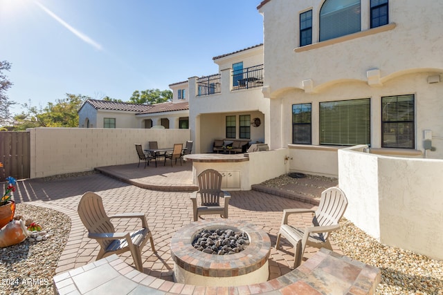 view of terrace with a fire pit and a balcony