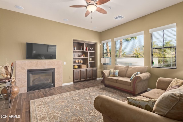 living room with dark hardwood / wood-style flooring, plenty of natural light, ceiling fan, and a fireplace