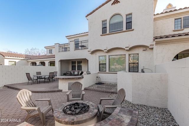 back of property with a patio, an outdoor fire pit, and a balcony