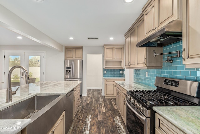 kitchen featuring a sink, decorative backsplash, under cabinet range hood, and stainless steel appliances