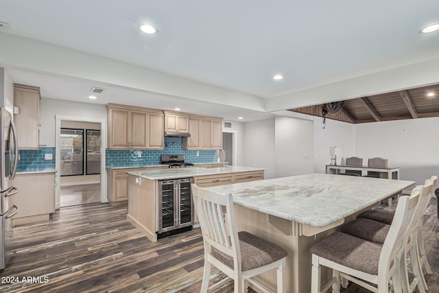 kitchen featuring visible vents, stainless steel gas range, an island with sink, a sink, and wine cooler