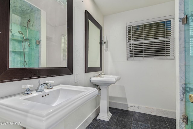 bathroom with baseboards, two sinks, and a shower stall