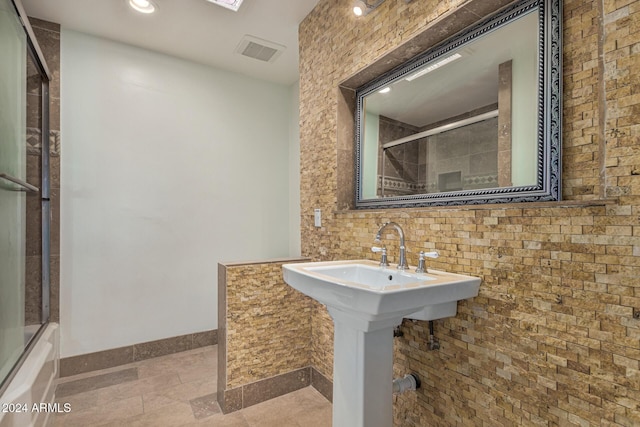 bathroom featuring visible vents, backsplash, baseboards, and shower / bath combination with glass door