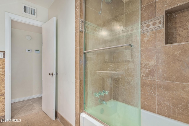 bathroom with baseboards, visible vents, and shower / bath combination with glass door