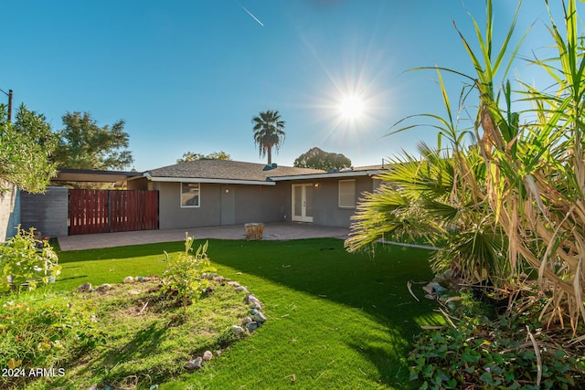 rear view of house featuring a yard, a patio area, fence, and stucco siding