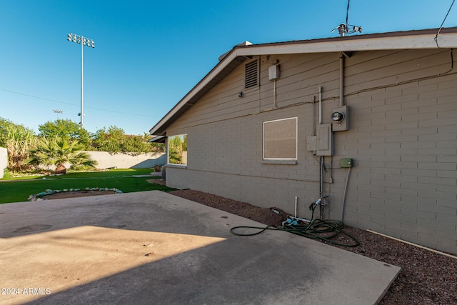 view of side of home featuring a patio area, a lawn, and brick siding