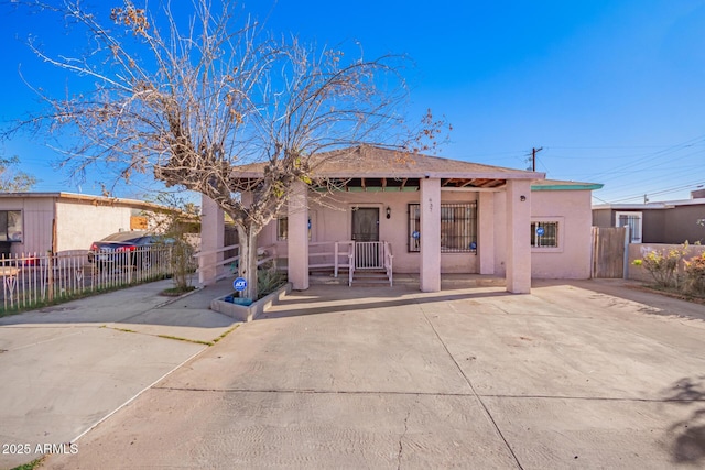 view of front of property featuring covered porch, fence, and stucco siding