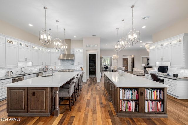 kitchen featuring a breakfast bar, a large island with sink, white cabinetry, and pendant lighting