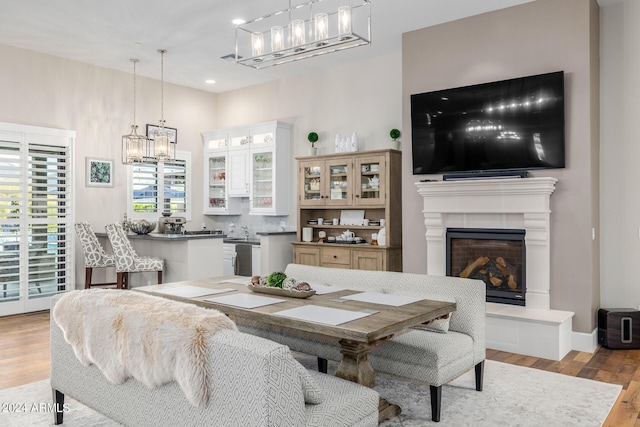 dining area with sink, a tile fireplace, and light hardwood / wood-style flooring