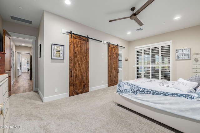 bedroom featuring a barn door, light colored carpet, and ceiling fan