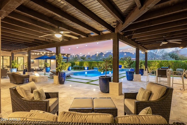 patio terrace at dusk with ceiling fan, a mountain view, and an outdoor hangout area