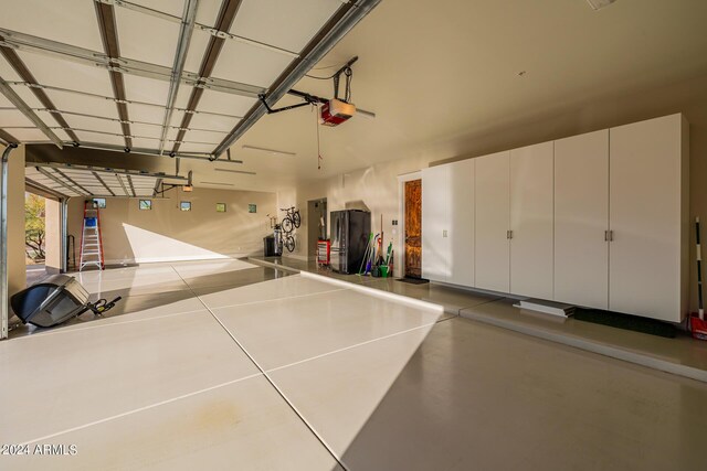 garage with stainless steel refrigerator and a garage door opener