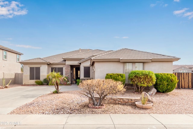 view of front of house with a tiled roof, fence, and stucco siding