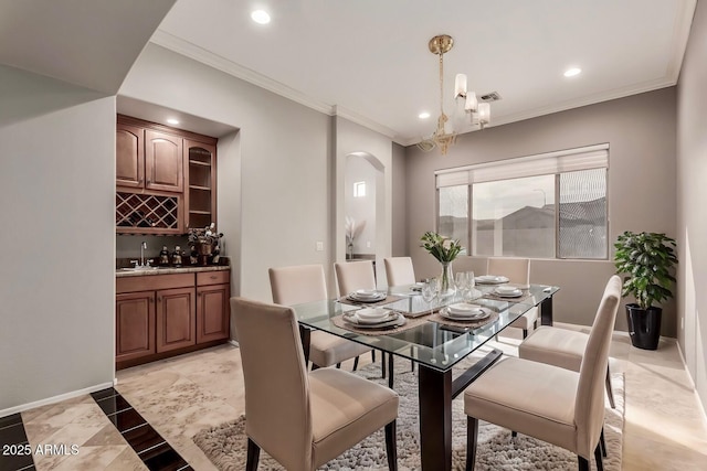 dining room with ornamental molding, wet bar, and an inviting chandelier