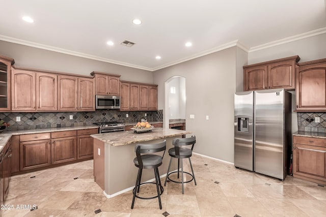 kitchen with tasteful backsplash, a kitchen bar, a center island, light stone counters, and stainless steel appliances