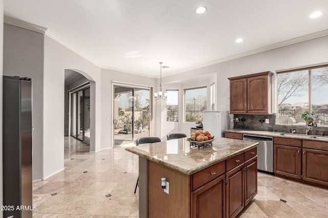 kitchen featuring sink, tasteful backsplash, hanging light fixtures, appliances with stainless steel finishes, and a kitchen island