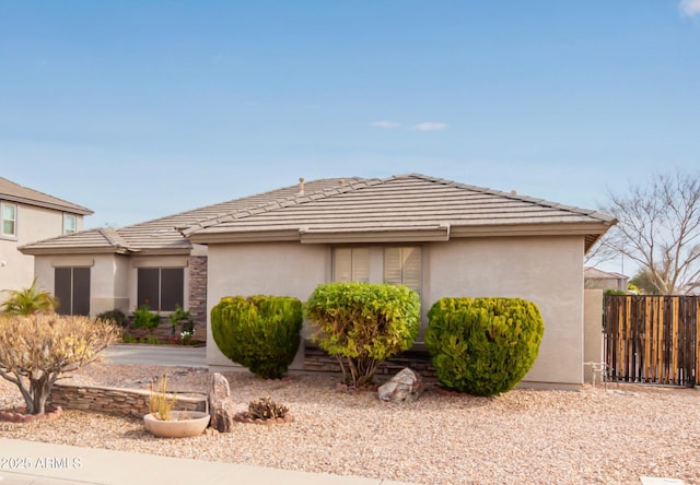 view of front of property with stucco siding, a tile roof, and fence