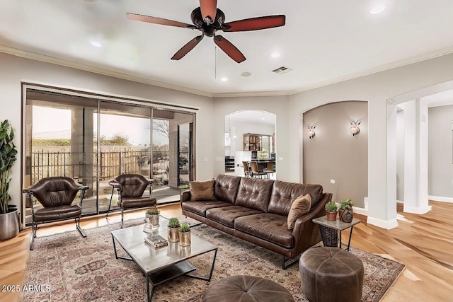 living room featuring crown molding, ceiling fan, and light wood-type flooring