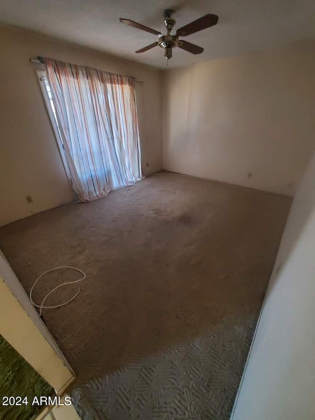 carpeted spare room with ceiling fan